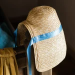 Chapeau de paille avec ruban bleu accroché à une chaise
