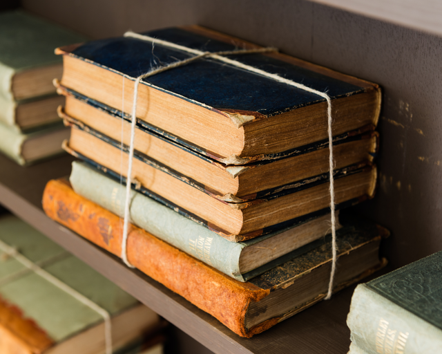 AKG4208362.webp Livres anciens empilés sur une étagère – Image 1