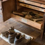 Vieille armoire en bois contenant des outils anciens et une paire de bottes usées