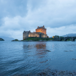 Château éclairé au bord d'un lac au crépuscule