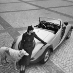 Femme et chien avec voiture classique sur une place pavée