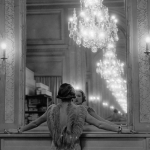 Femme en robe élégante devant un miroir avec lustre