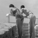 Couple en maillots de bain regardant la mer depuis un balcon
