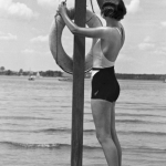 Femme en maillot de bain tenant une bouée de sauvetage sur la plage