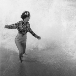 Femme sur la plage échappant à une vague