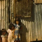 Enfants devant une maison en tôle