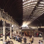 Gare avec voyageurs sous une verrière architecturale