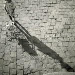 Enfant avec une poussette sur une place pavée.