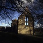 Ruine d'un bâtiment ancien éclairé par le soleil derrière des arbres en hiver