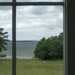 Vue sur un champ et un lac à travers une fenêtre
