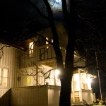 Maison en bois éclairée par la lune à travers les arbres
