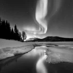 Aurore boréale sur une rivière glacée en noir et blanc