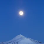 Pleine lune au-dessus d'un sommet enneigé