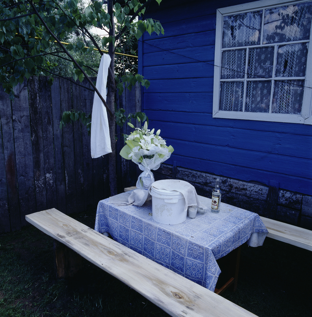 AKG453049.webp Table de jardin avec nappe bleue et seau blanc – Image 1