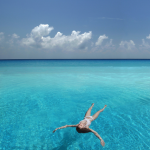 Femme flottant dans une eau turquoise sous un ciel bleu