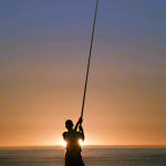 Pêcheur au coucher du soleil sur la plage