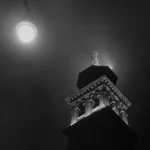 Statue illuminée sur une tour au clair de lune