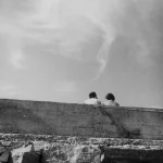 Deux personnes assises sur un mur en extérieur