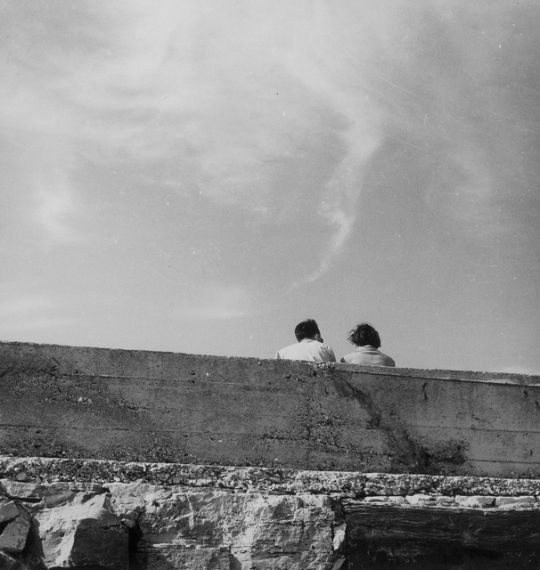 AKG4560524.webp Deux personnes assises sur un mur en extérieur – Image 1