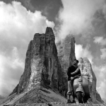 Homme avec scooter devant montagnes en noir et blanc
