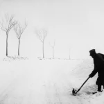 Personne pelletant la neige sur une route enneigée