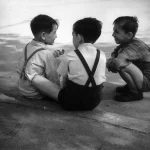 Trois garçons discutant assis près d'un plan d'eau