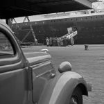 Groupe de personnes près d'un navire avec une voiture à l'avant
