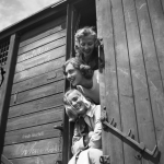 Trois femmes souriantes à la porte d'un wagon en bois