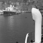 Vue d'un port avec des passagers, un grand paquebot et des bâtiments en arrière-plan