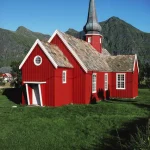 Église rouge traditionnelle au pied des montagnes