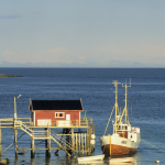 Cabane rouge au bord de la mer avec un bateau de pêche