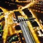 Vue aérienne nocturne d'une ville européenne avec gares et rues illuminées.
