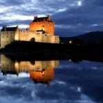 Château éclairé avec reflet dans l'eau au crépuscule