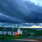 Maison traditionnelle avec cabine téléphonique sous un ciel nuageux au crépuscule