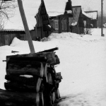 Village enneigé avec maisons en bois et tas de bûches