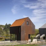 Maison moderne en bois avec toit rouillé dans un cadre rural