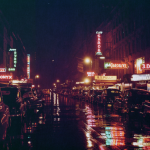 Rue de nuit avec néons et voitures anciennes