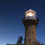Phare illuminé sous un ciel étoilé nocturne