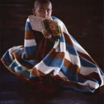 Moine enfant lisant sous une couverture colorée