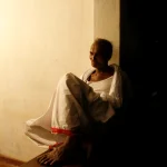 Homme âgé assis pensivement dans un coin sombre