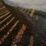 Ombres des Pierres sur la Plage au Coucher du Soleil