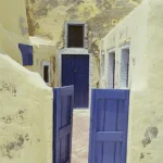 Portes bleues et murs jaunes dans une ruelle méditerranéenne
