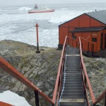 Bâtiment orange sur une île avec un navire en arrière-plan
