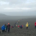 Randonneurs sur un terrain volcanique dans une ambiance brumeuse