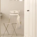 Chaise blanche pliable avec sac en tissu dans une pièce blanche