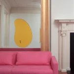 Canapé rose vibrant devant un miroir doré et décoration murale
