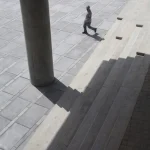 Homme marchant près des escaliers d'un bâtiment moderne