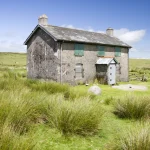Ferme abandonnée dans les prairies verdoyantes sous un ciel bleu