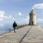 Personne marchant avec un chien près du phare en bord de mer