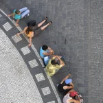 Groupe de personnes assises sur une place pavée vue de dessus